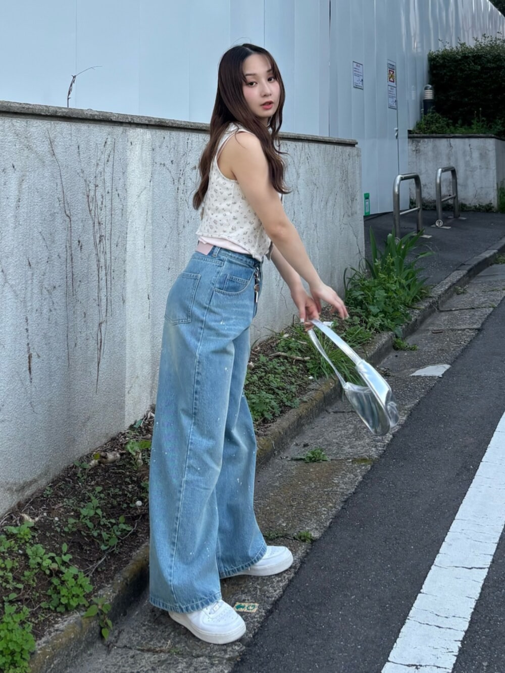 ピンク系のベスト、ピンク系のキャミソール、ブルー系のデニムパンツを着用したレディースの春コーディネートの3枚目の写真