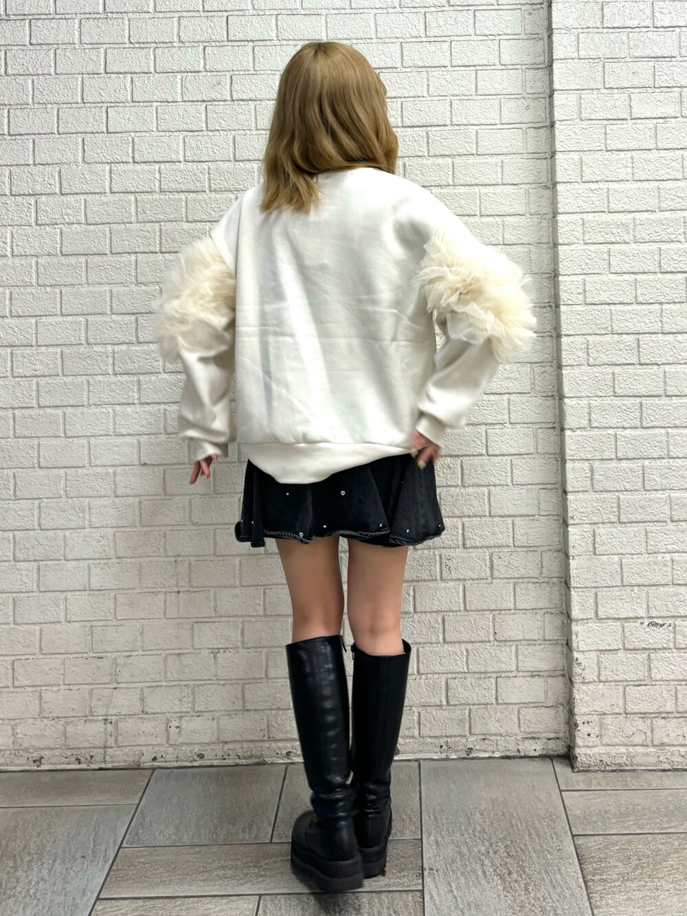 ホワイト系のスウェット、ブラック系のブーツ、ブルー系のスカートを着用したレディースの秋コーディネートの3枚目の写真