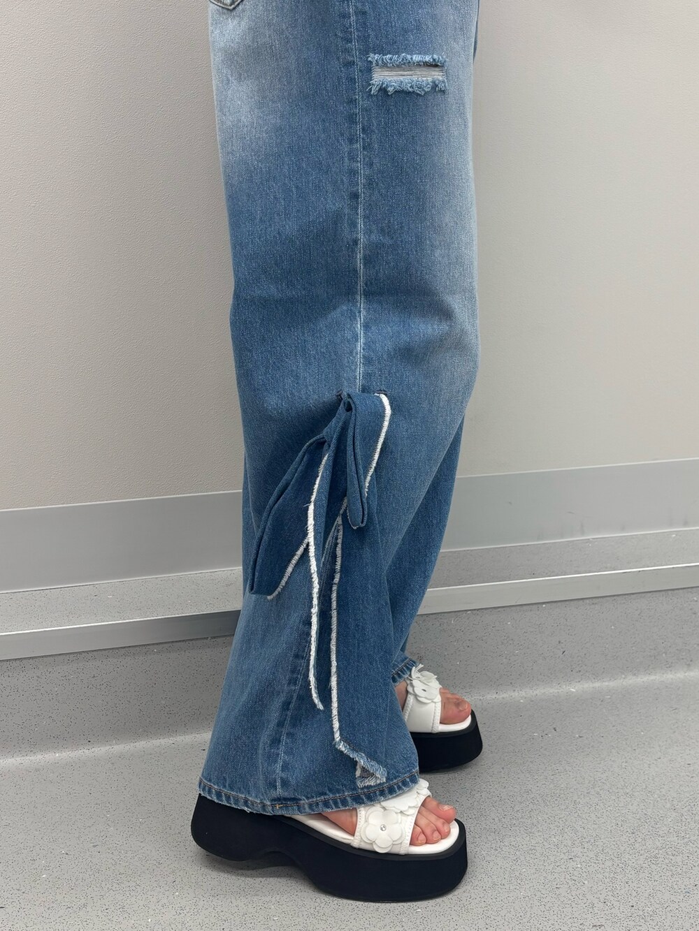ブルー系のデニムパンツ、ブルー系のポロシャツ、ホワイト系のサンダルを着用したレディースの春コーディネートの6枚目の写真
