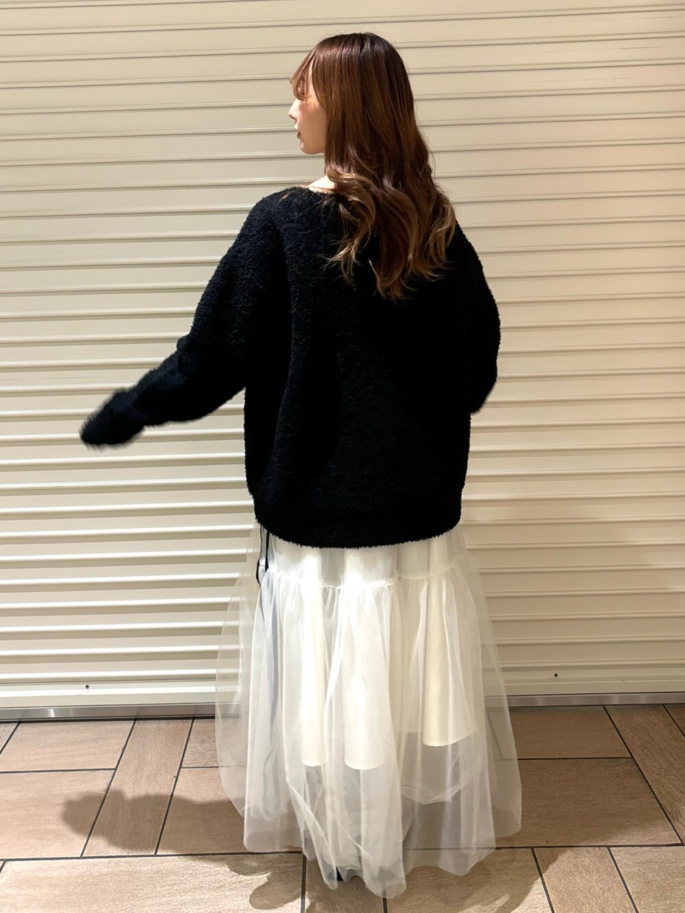 ブラック系のニット/セーター、ホワイト系のスカート、ホワイト系のブーツを着用したレディースの秋コーディネートの4枚目の写真