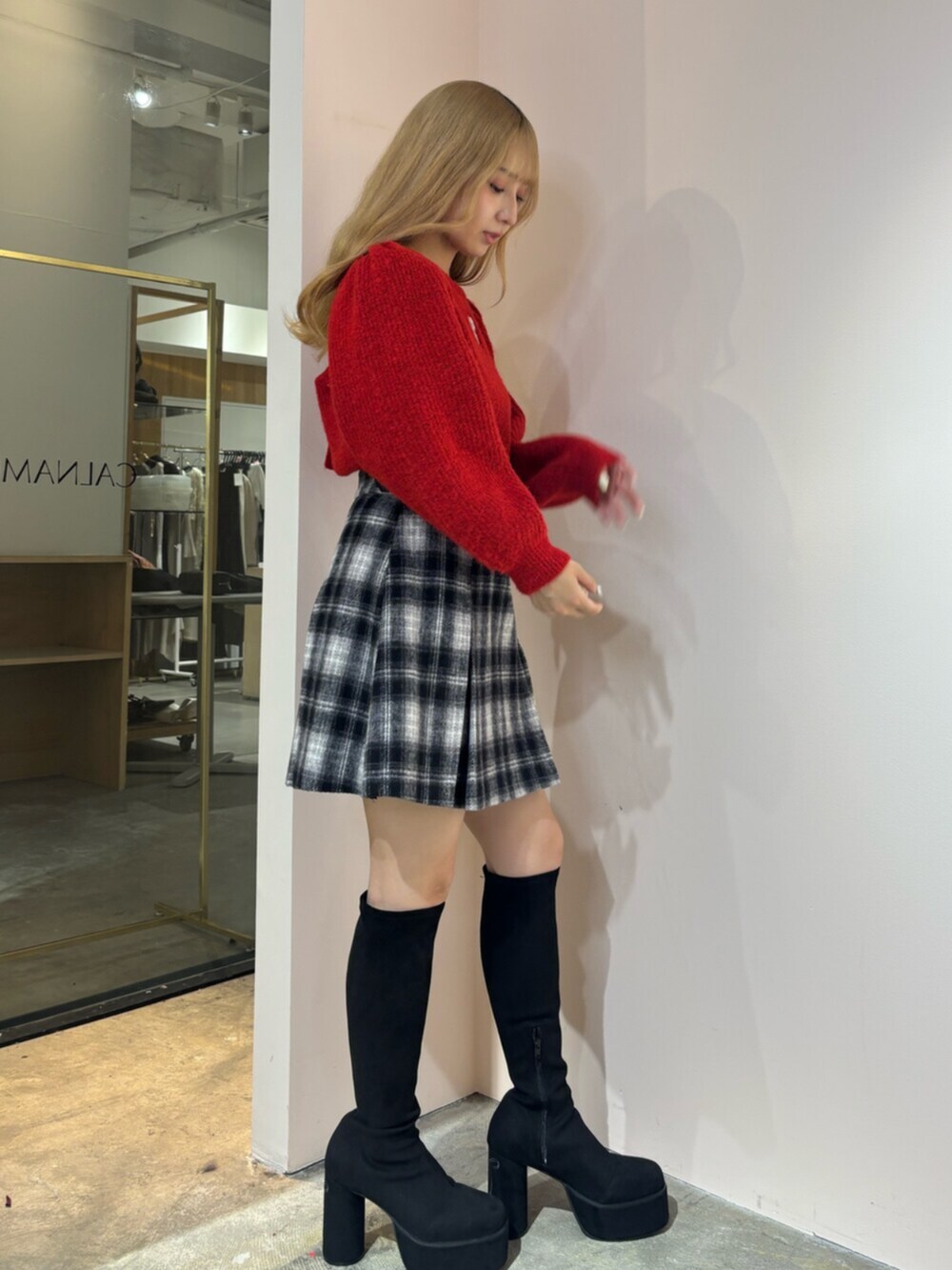 ブラック系のブーツ、レッド系のニット/セーター、その他のスカートを着用したレディースの秋コーディネートの2枚目の写真