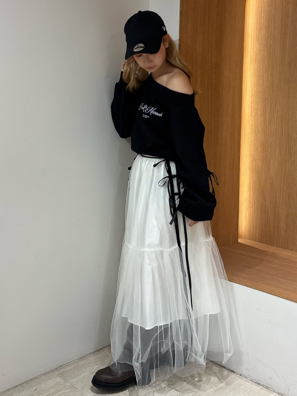 ホワイト系のスカート、ブラック系のスウェット、ブラウン系のブーツを着用したレディースの秋コーディネートの2枚目の写真