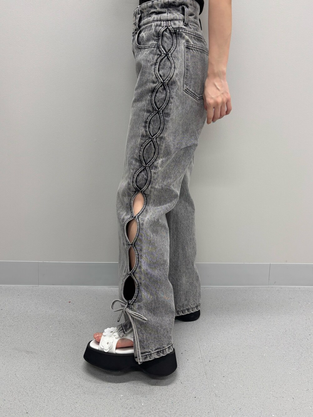 ブルー系のデニムパンツ、ブラック系のニット/セーター、ホワイト系のサンダルを着用したレディースの春コーディネートの5枚目の写真