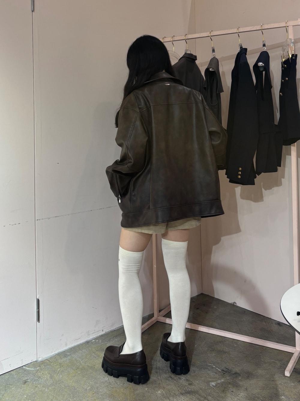 ブラウン系のライダースジャケット、ホワイト系のニット/セーター、ブラウン系のローファーを着用したレディースの秋コーディネートの4枚目の写真