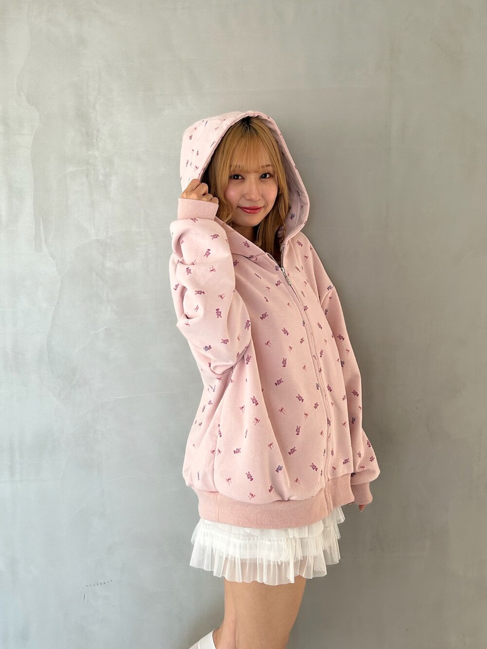 ピンク系のパーカー、ホワイト系のスカート、ピンク系のパンプスを着用したレディースの春コーディネートの8枚目の写真