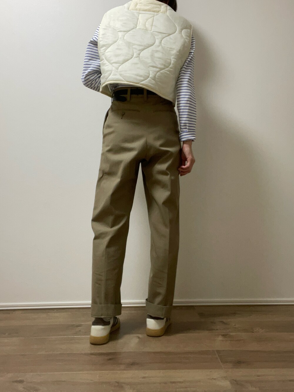 ホワイト系のベスト、ベージュ系のチノパンツ、ホワイト系のスニーカーを着用したレディースの春コーディネートの5枚目の写真