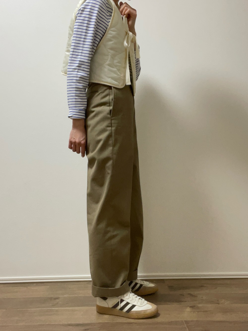 ホワイト系のベスト、ベージュ系のチノパンツ、ホワイト系のスニーカーを着用したレディースの春コーディネートの4枚目の写真