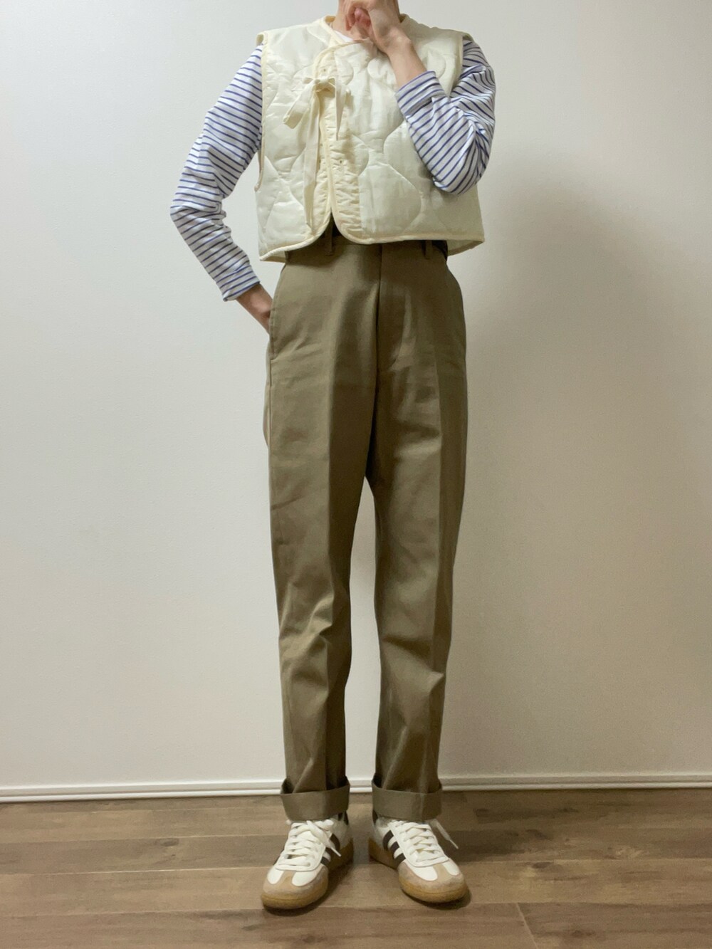 ホワイト系のベスト、ベージュ系のチノパンツ、ホワイト系のスニーカーを着用したレディースの春コーディネートの3枚目の写真