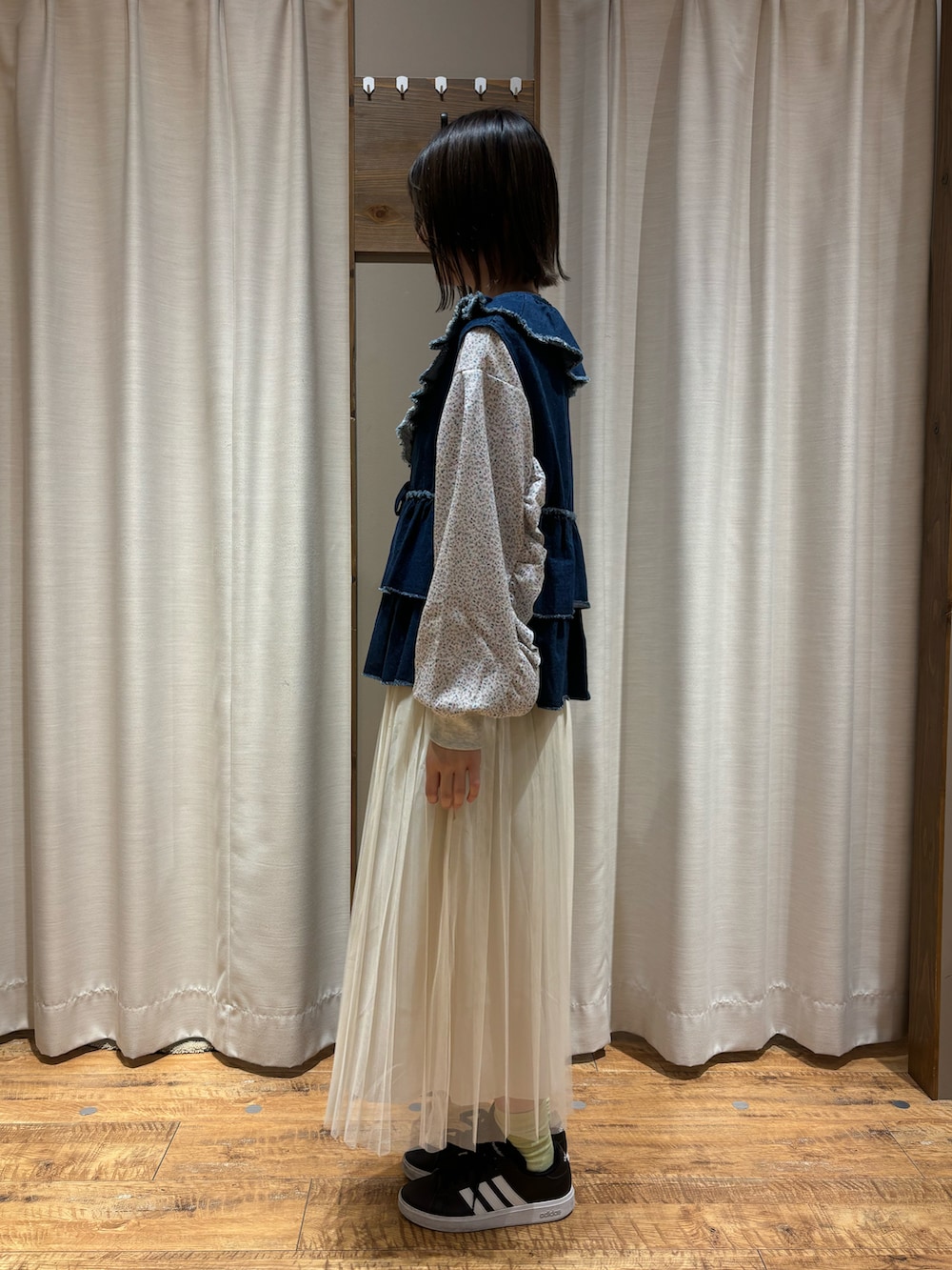 ブルー系のベスト、グレー系のTシャツ/カットソー、ホワイト系のスカートを着用したレディースの秋コーディネートの2枚目の写真