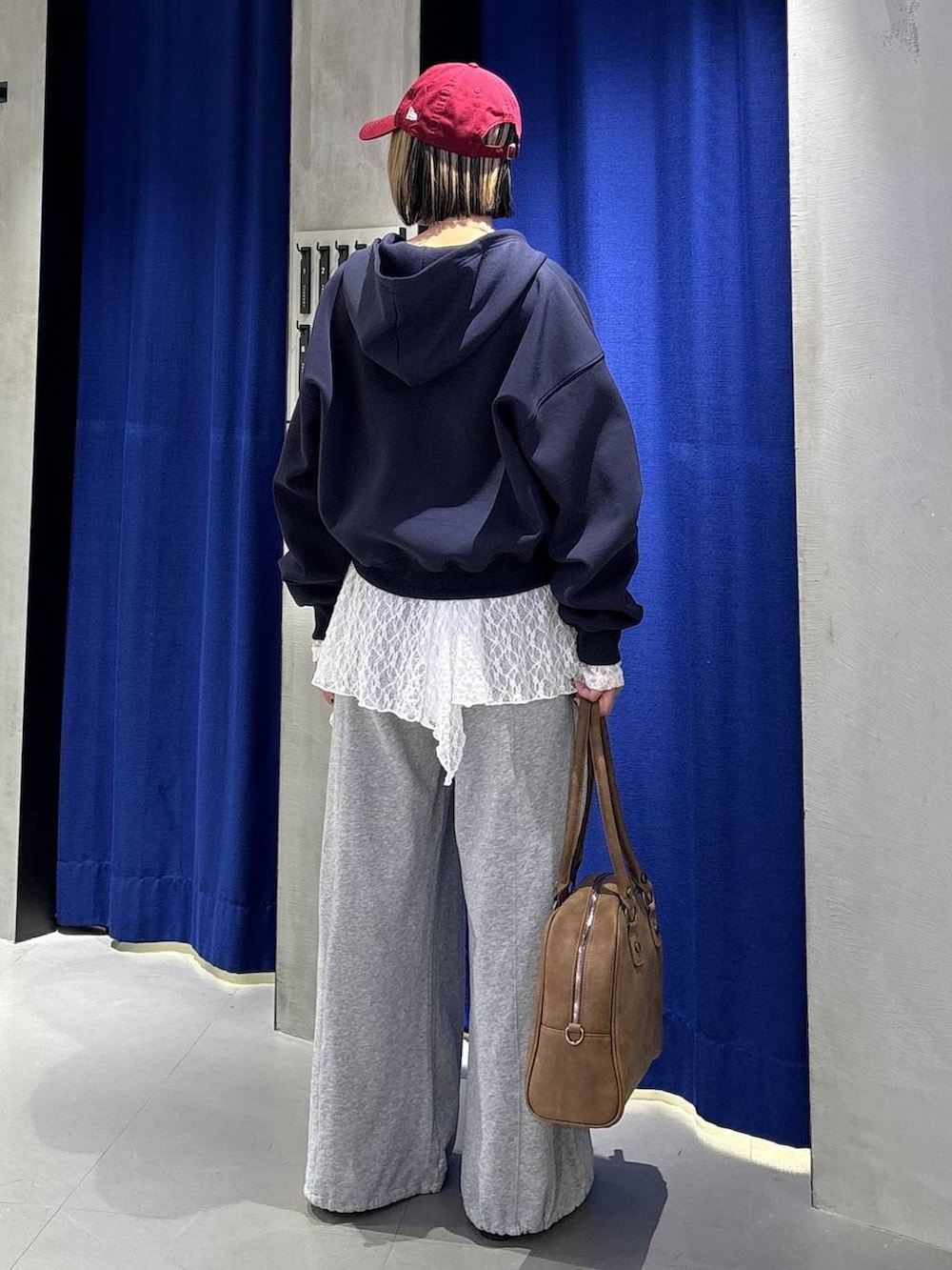 イエロー系のボストンバッグ、ブルー系のパーカー、グレー系のスウェットパンツを着用したレディースの冬コーディネートの6枚目の写真