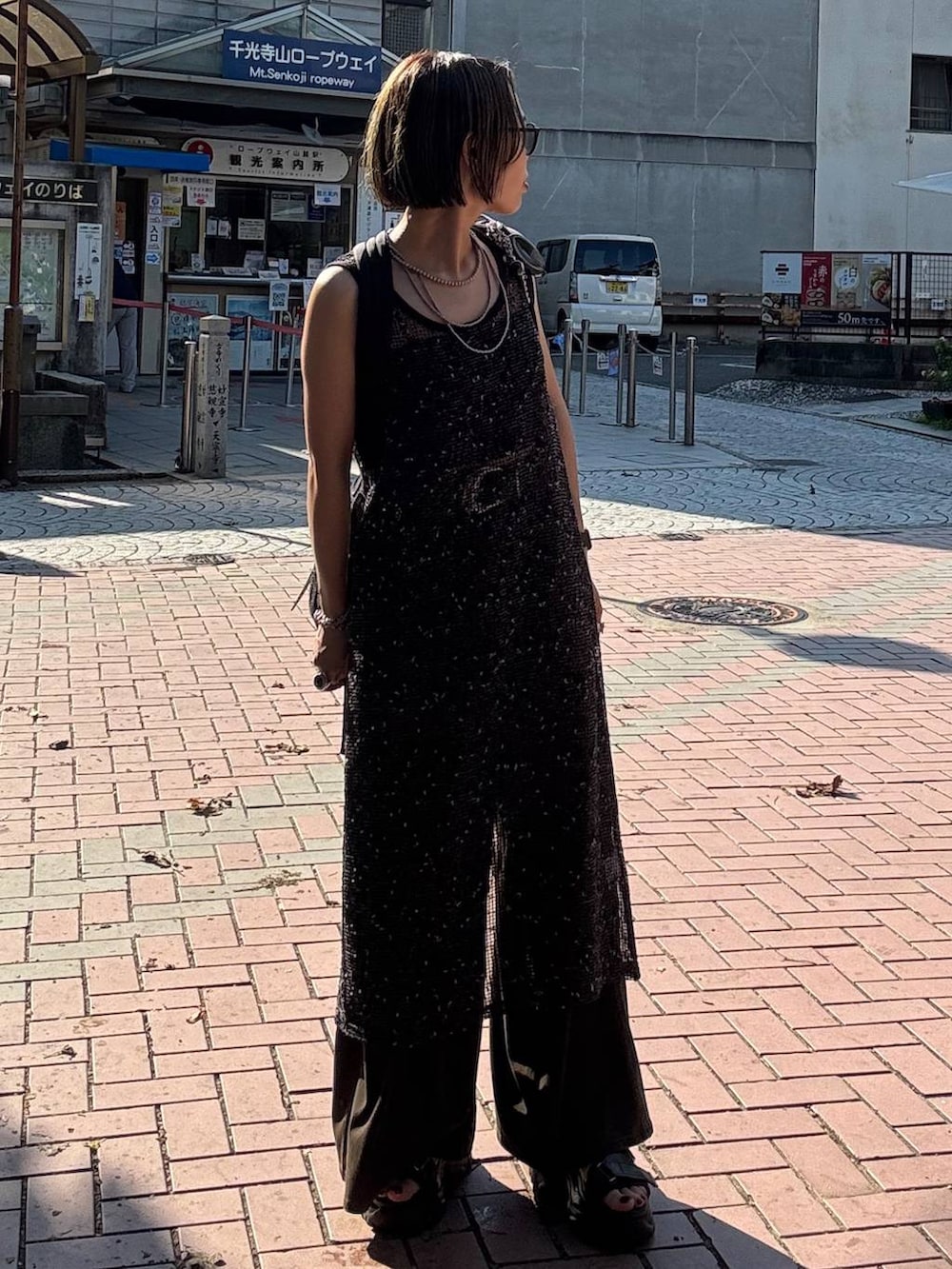 ブラウン系のデニムパンツ、ブラック系のサンダル、ブラック系のワンピースを着用したレディースの夏コーディネートの3枚目の写真