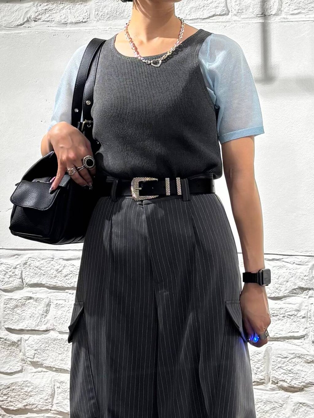 ブラック系のハンドバッグ、グレー系のスラックス、ブルー系のTシャツ/カットソーを着用したレディースの夏コーディネートの3枚目の写真