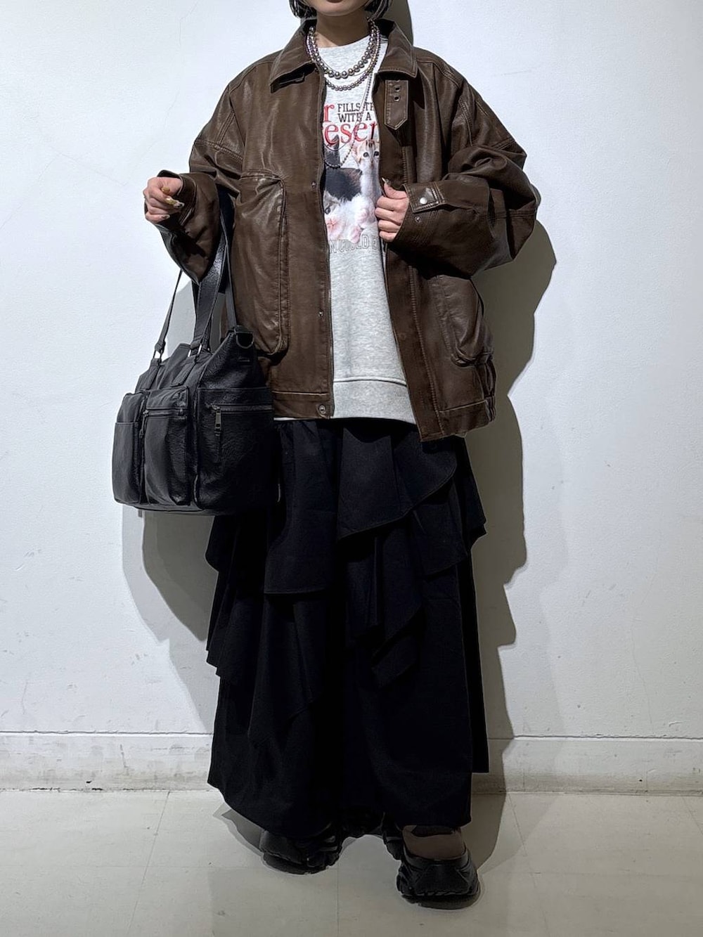 ブラウン系のブーツ、ブラック系のボストンバッグ、ブラック系のスカートを着用したレディースの冬コーディネートの2枚目の写真