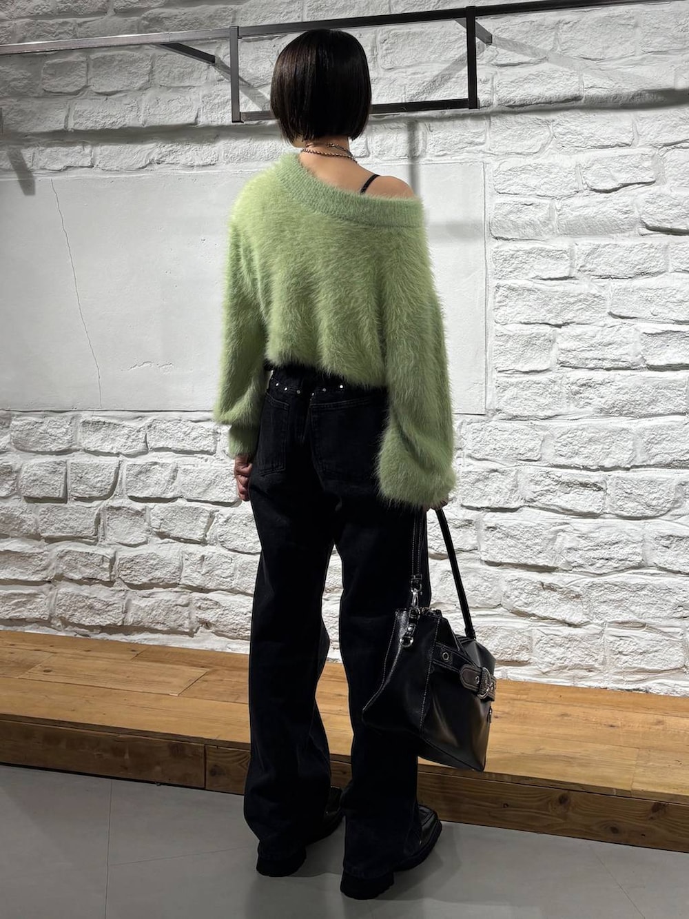 ブラック系のブーツ、ブラック系のデニムパンツ、ブラック系のショルダーバッグを着用したレディースの秋コーディネートの5枚目の写真