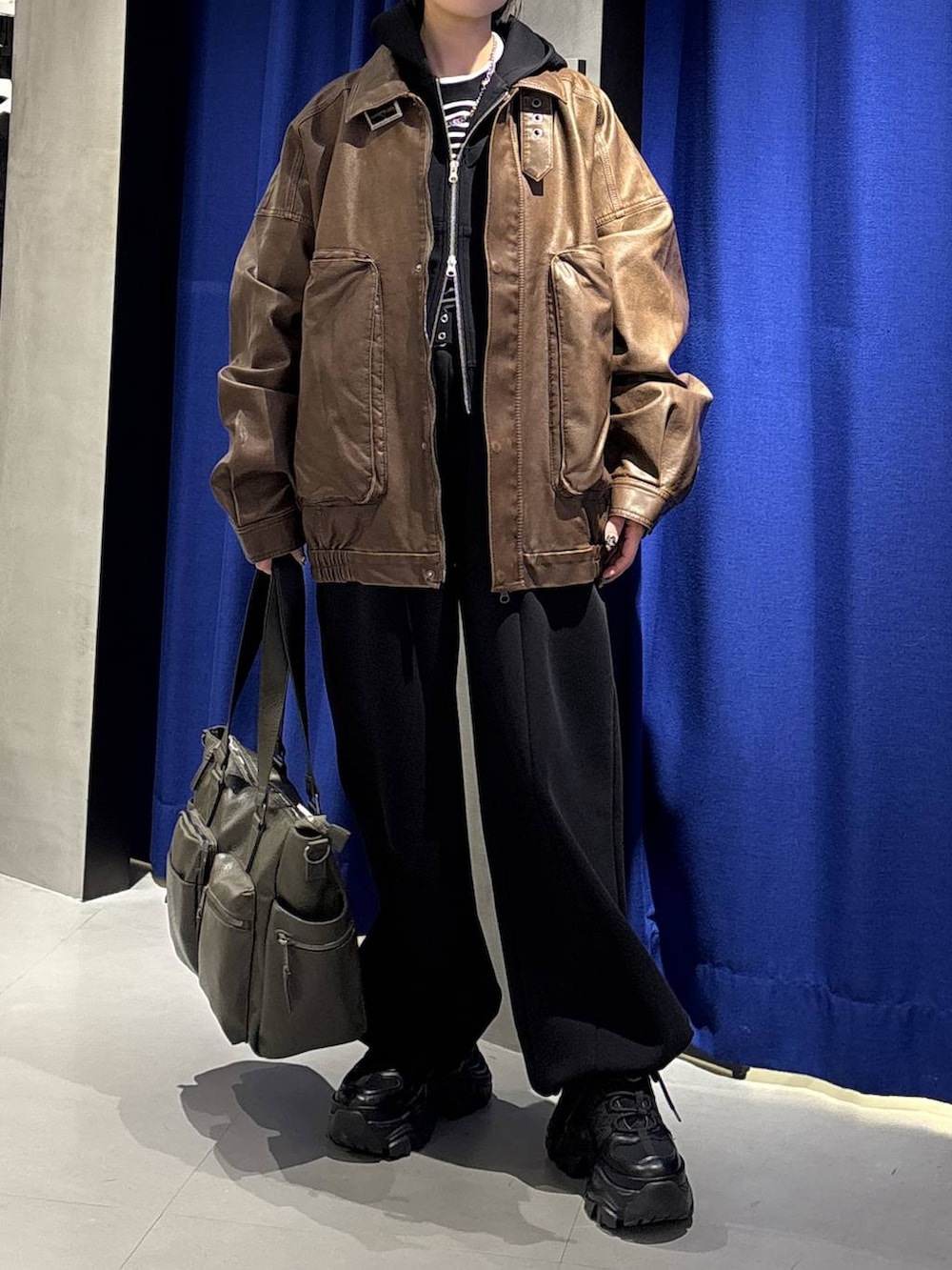 ブラック系のスニーカー、グリーン系のボストンバッグ、ブラック系のTシャツ/カットソーを着用したレディースの冬コーディネートの2枚目の写真