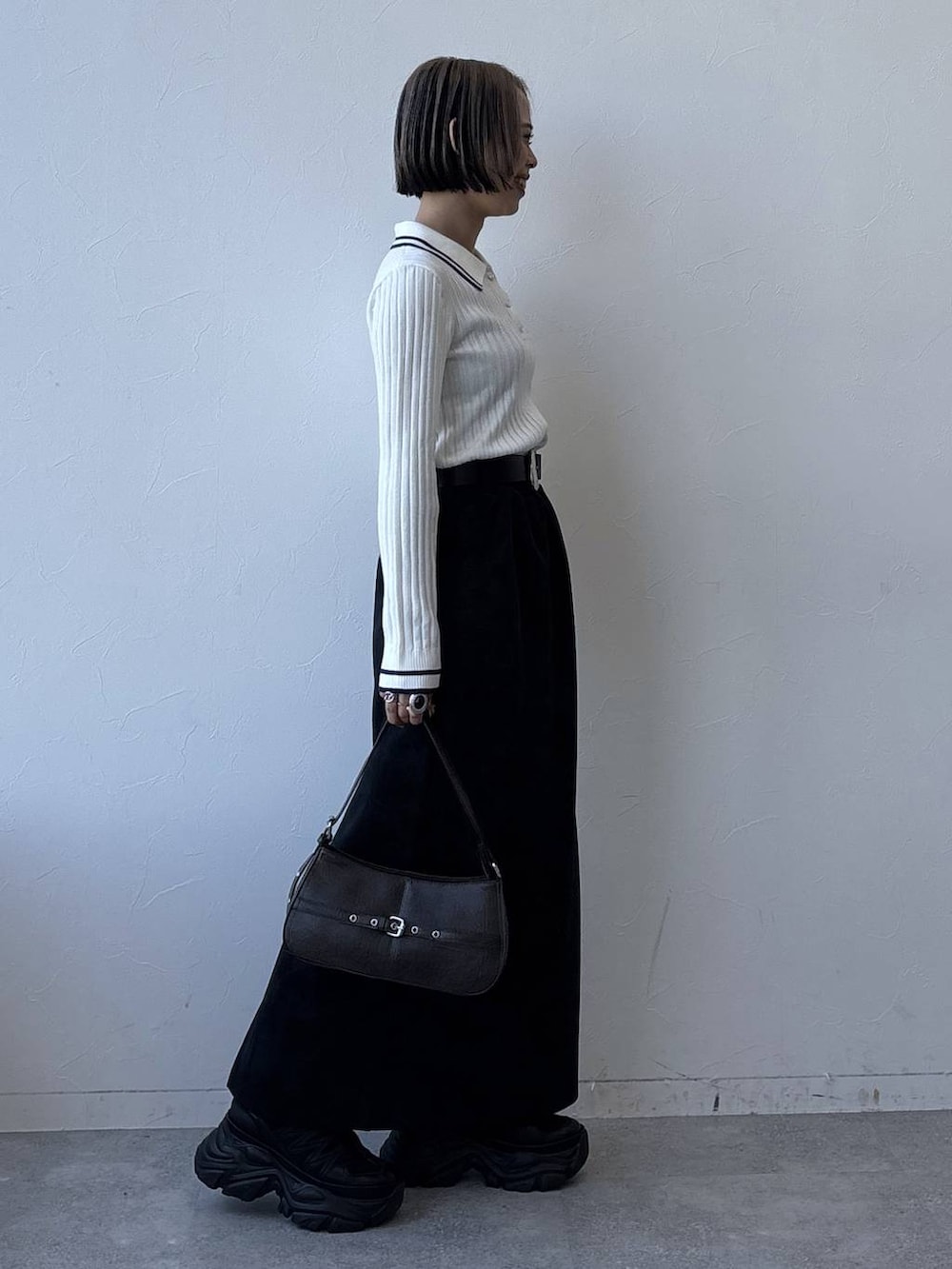 グレー系のスニーカー、ブラック系のスカート、ホワイト系のニット/セーターを着用したレディースの冬コーディネートの5枚目の写真