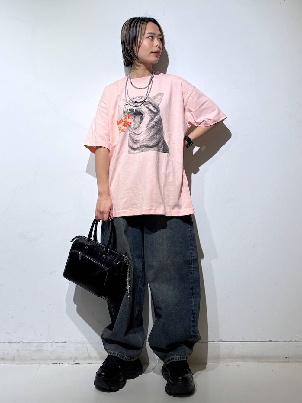 ブラック系のスニーカー、ブルー系のデニムパンツ、ブラック系のショルダーバッグを着用したレディースの春コーディネートの2枚目の写真