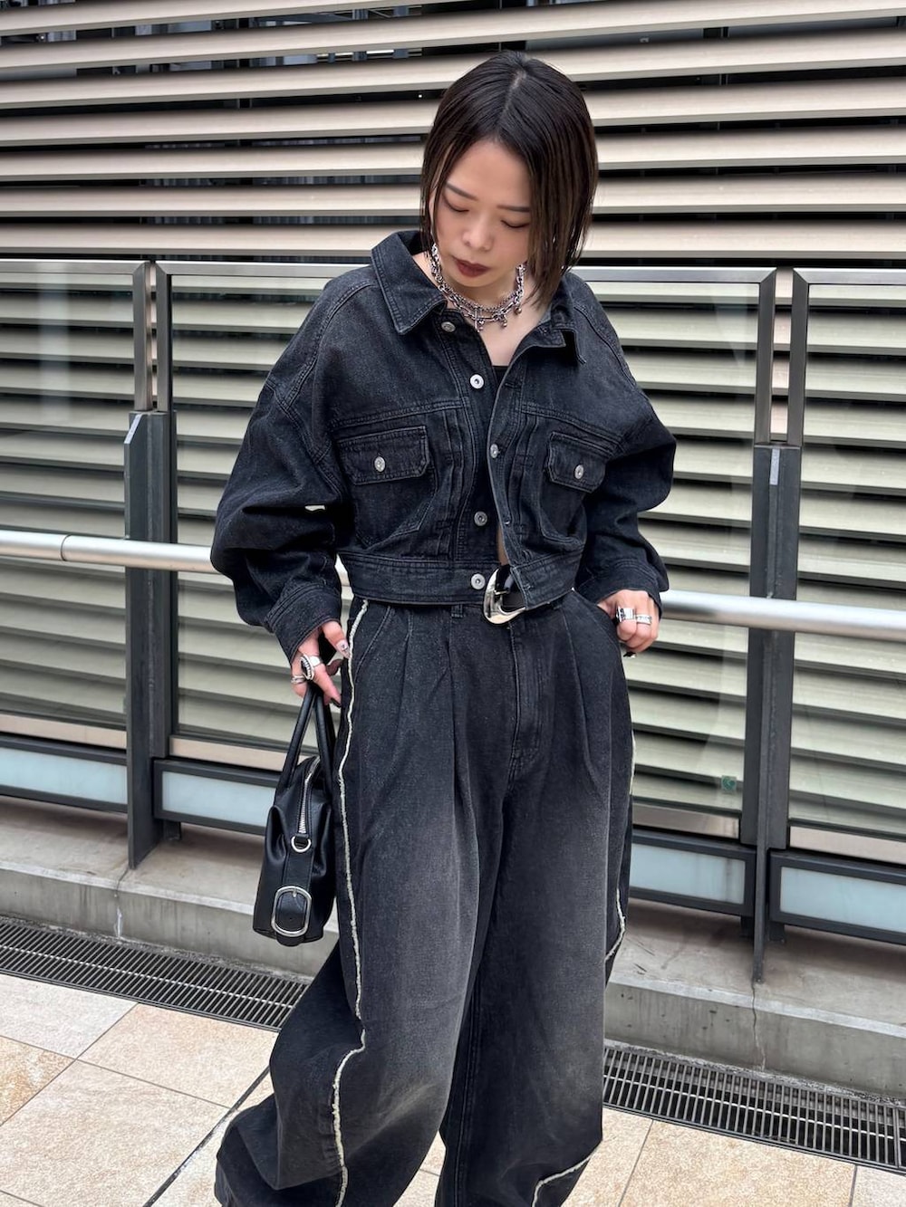 ブラック系のショルダーバッグ、ブラック系のデニムジャケット、ブラック系のデニムパンツを着用したレディースの秋コーディネートの4枚目の写真