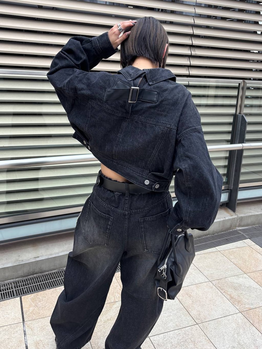 ブラック系のショルダーバッグ、ブラック系のデニムジャケット、ブラック系のデニムパンツを着用したレディースの秋コーディネートの6枚目の写真