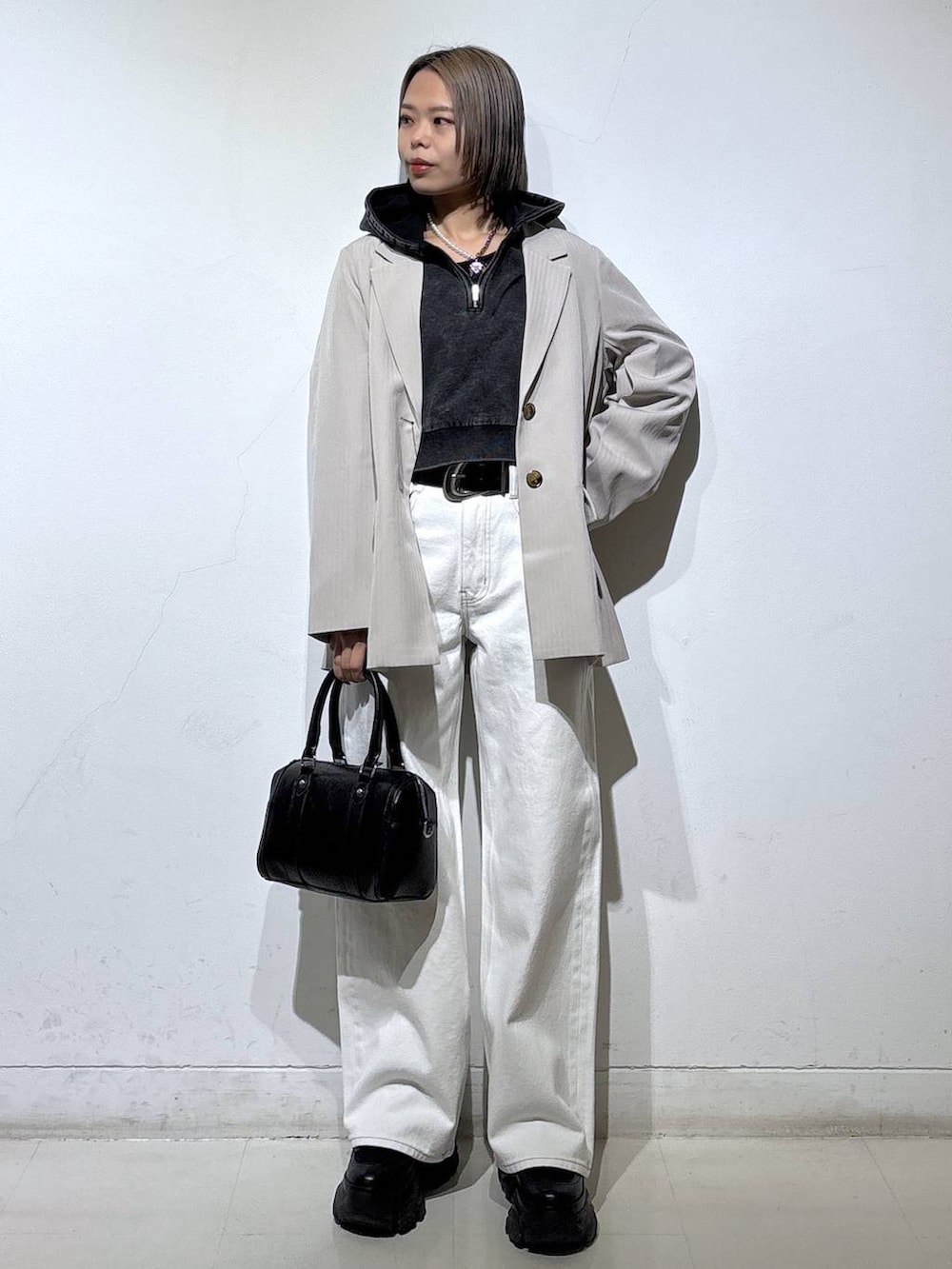 ブラック系のブーツ、ブラック系のTシャツ/カットソー、ホワイト系のスラックスを着用したレディースの冬コーディネートの3枚目の写真