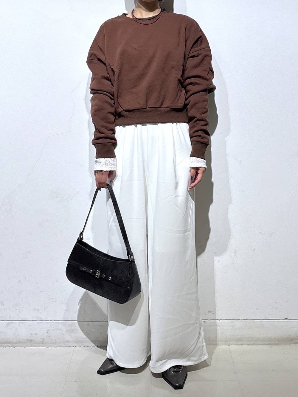 ブラウン系のスウェット、ブラック系のハンドバッグ、ブラック系のサンダルを着用したレディースの春コーディネートの2枚目の写真