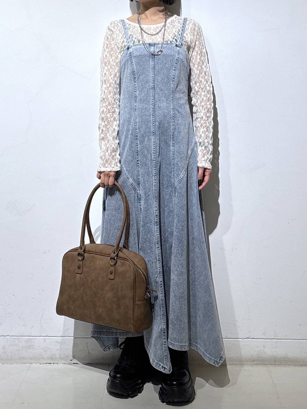 ブラック系のブーツ、ベージュ系のボストンバッグ、ブルー系のワンピースを着用したレディースの冬コーディネートの2枚目の写真