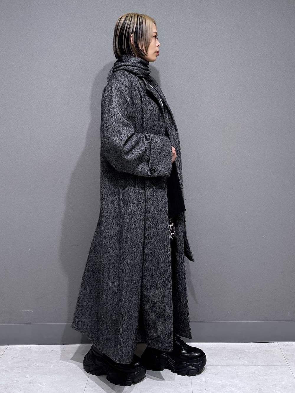 ブラック系のブーツ、ブラック系のチェスターコート、ホワイト系のTシャツ/カットソーを着用したレディースの冬コーディネートの3枚目の写真