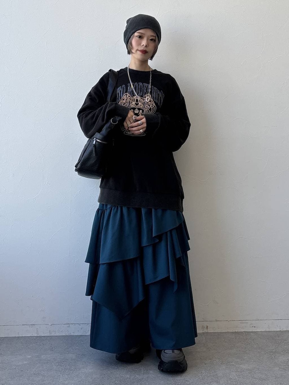 グレー系のスニーカー、ブラック系のボストンバッグ、ブルー系のスカートを着用したレディースの冬コーディネートの2枚目の写真