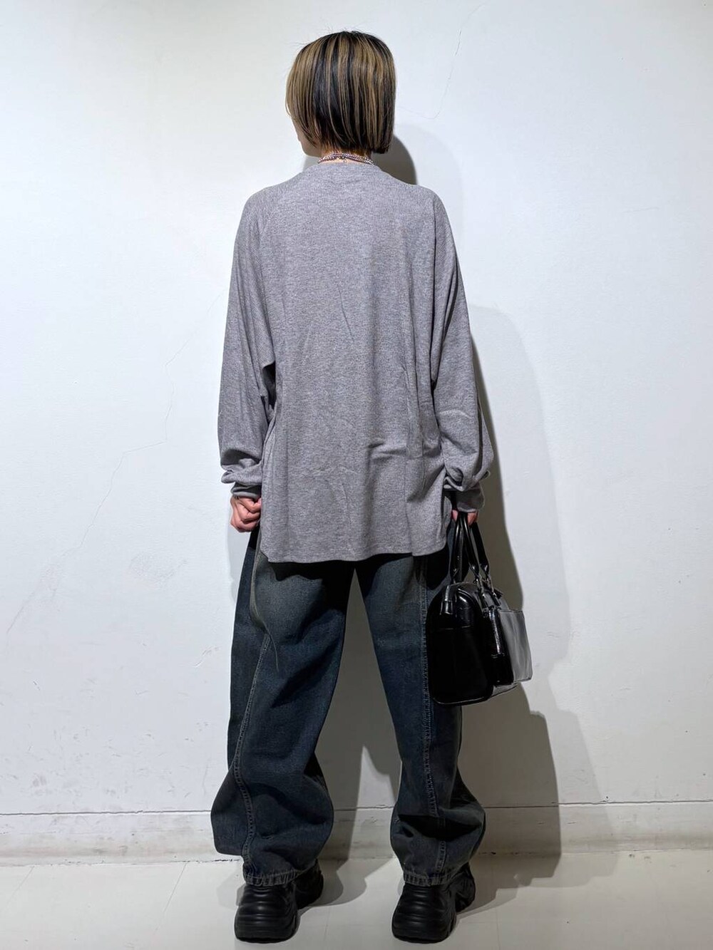 ブラック系のスニーカー、ブルー系のデニムパンツ、ブラック系のショルダーバッグを着用したレディースの春コーディネートの5枚目の写真