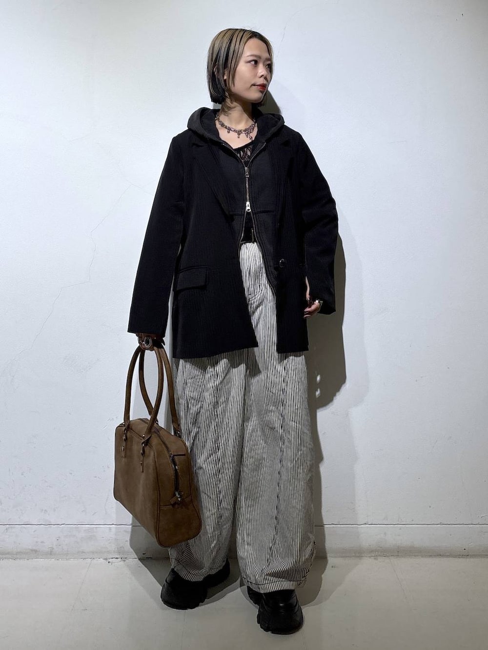 ブラック系のブーツ、ベージュ系のボストンバッグ、ブラック系のTシャツ/カットソーを着用したレディースの冬コーディネートの4枚目の写真