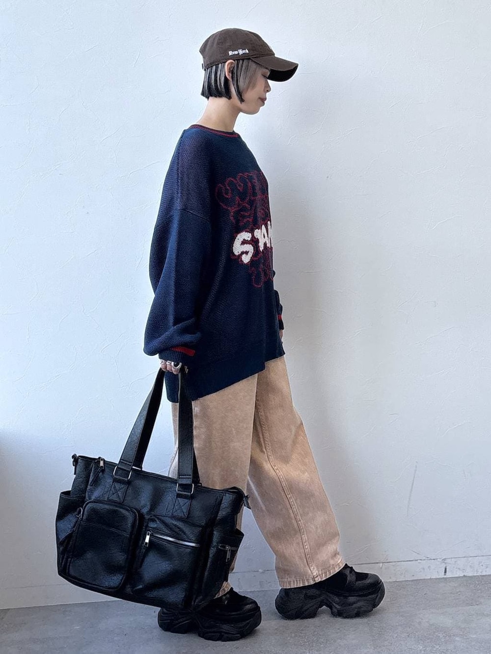 ブラック系のスニーカー、ブラック系のボストンバッグ、ブラウン系のデニムパンツを着用したレディースの冬コーディネートの3枚目の写真