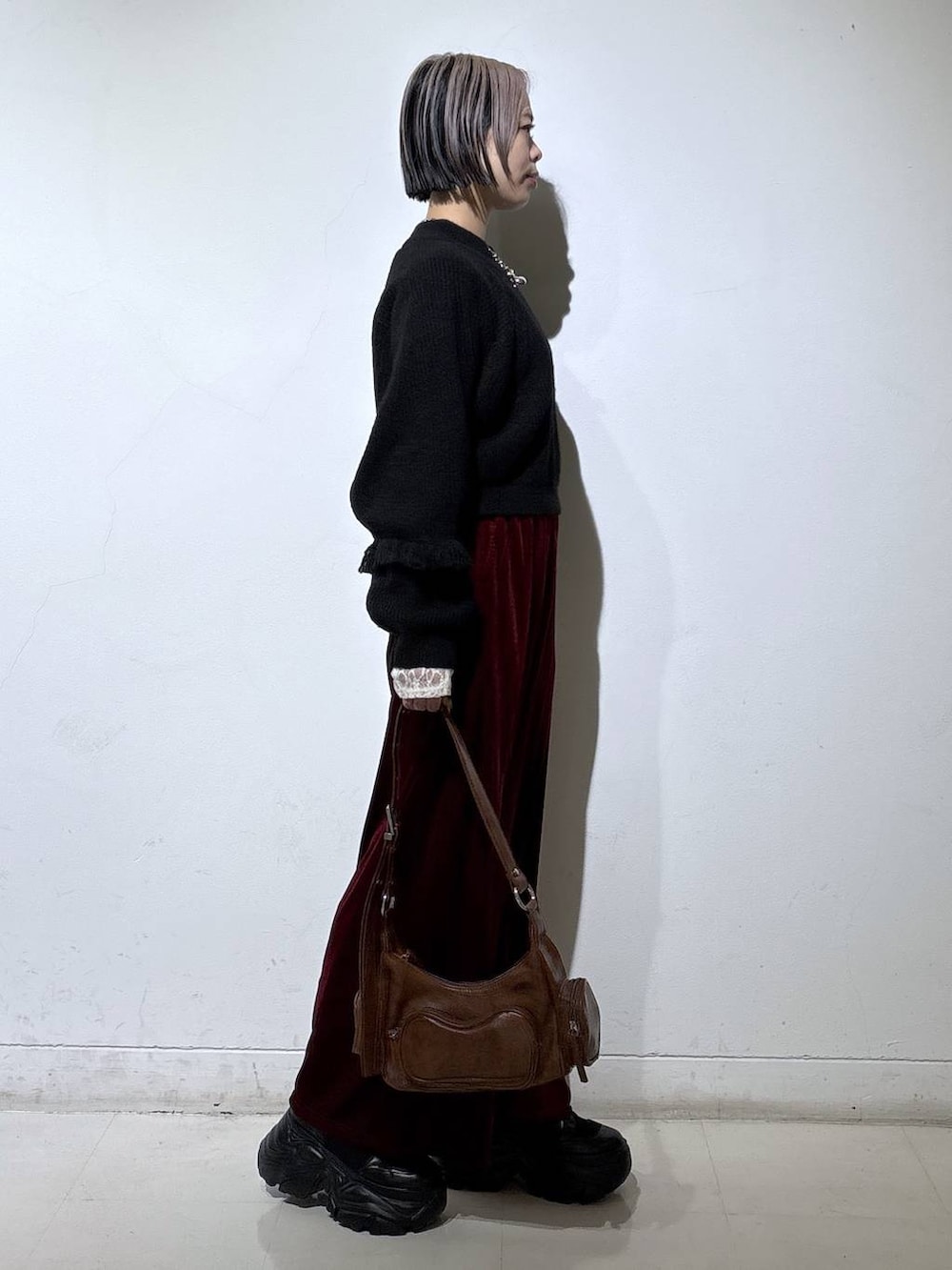 ブラック系のブーツ、ホワイト系のTシャツ/カットソー、ブラウン系のショルダーバッグを着用したレディースの冬コーディネートの3枚目の写真