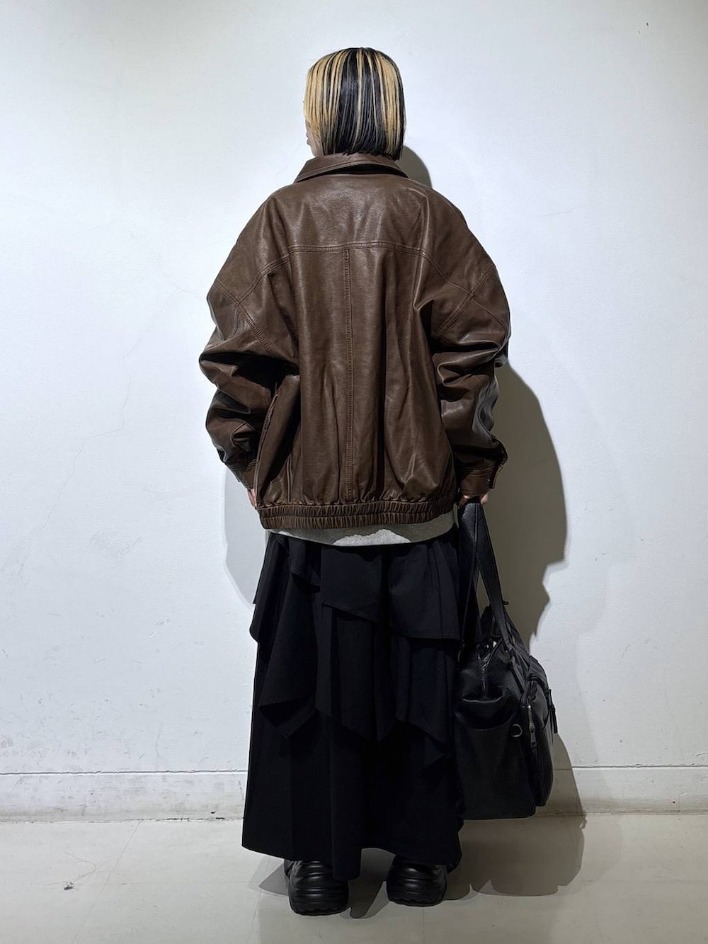 ブラウン系のブーツ、ブラック系のボストンバッグ、ブラック系のスカートを着用したレディースの冬コーディネートの4枚目の写真