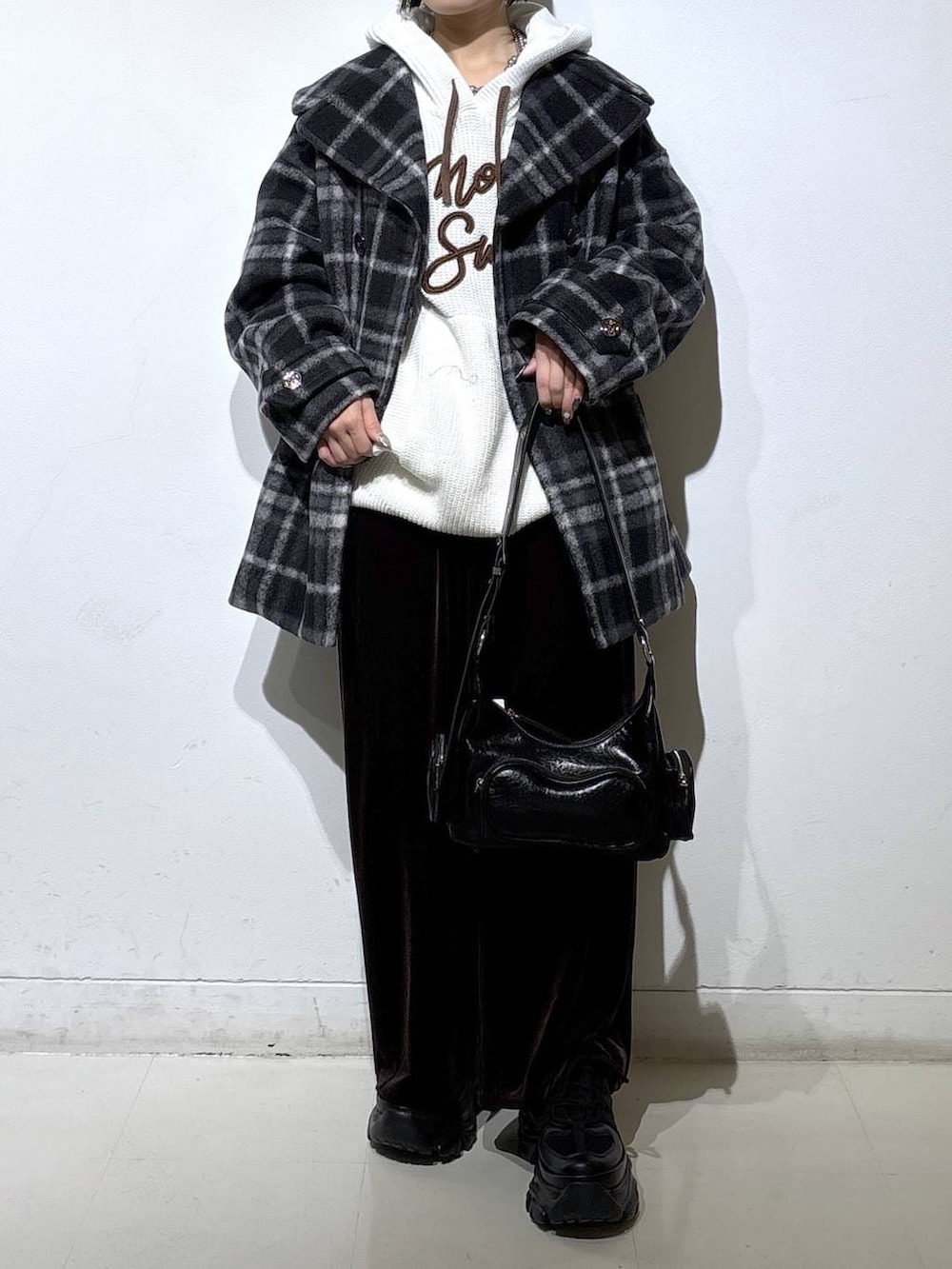 ブラック系のブーツ、ブラック系のチェスターコート、ホワイト系のパーカーを着用したレディースの秋コーディネートの2枚目の写真