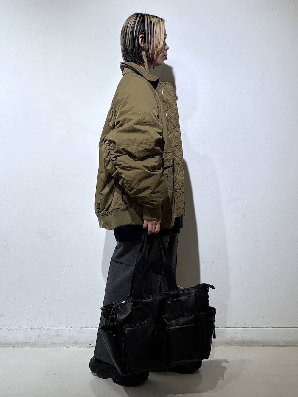 ブラック系のブーツ、ブラック系のボストンバッグ、ブルー系のニット/セーターを着用したレディースの冬コーディネートの3枚目の写真