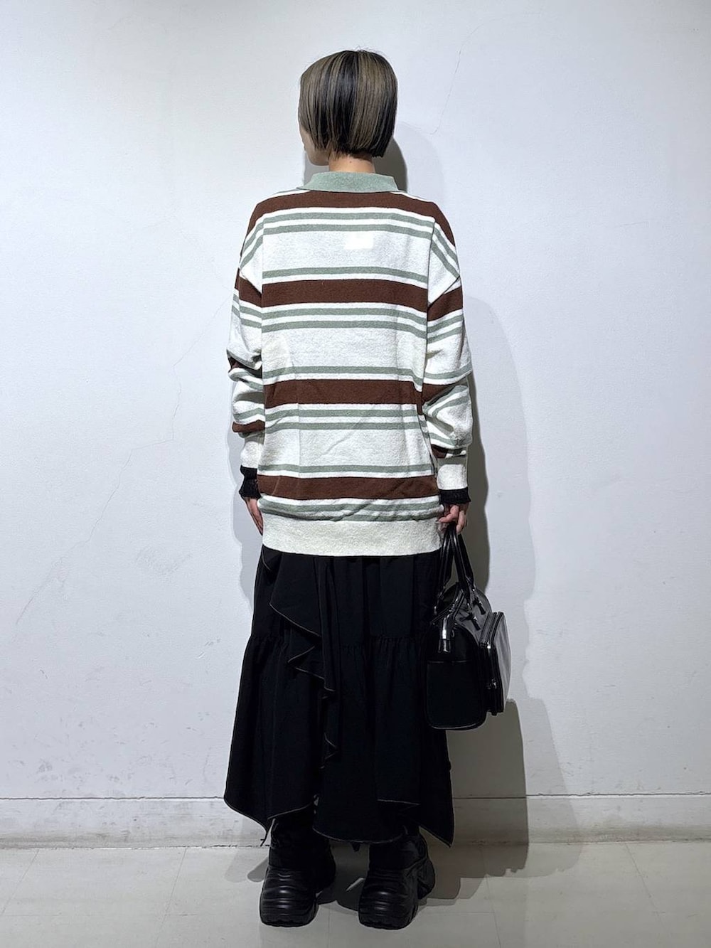 ブラック系のスニーカー、ブラック系のスカート、ブラック系のショルダーバッグを着用したレディースの春コーディネートの4枚目の写真