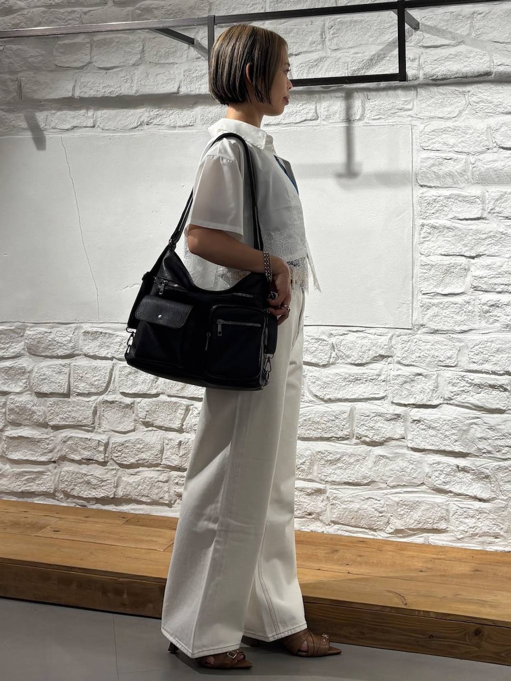 ブラック系のデニムパンツ、ブラック系のショルダーバッグ、イエロー系のサンダルを着用したレディースの春コーディネートの4枚目の写真