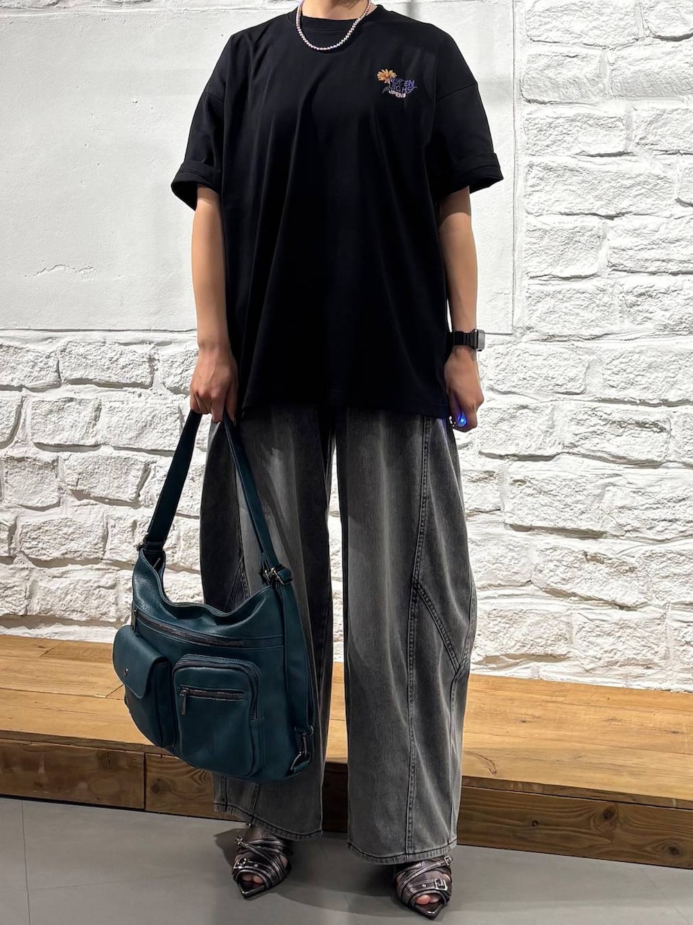 ブルー系のショルダーバッグ、ブラック系のデニムパンツ、イエロー系のサンダルを着用したレディースの春コーディネートの3枚目の写真