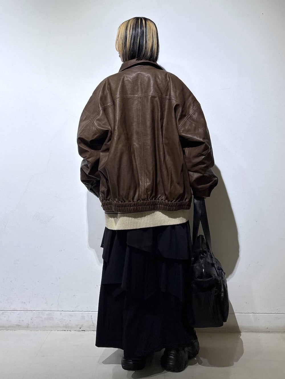 ブラウン系のブーツ、ブラック系のボストンバッグ、ブラック系のスカートを着用したレディースの冬コーディネートの4枚目の写真