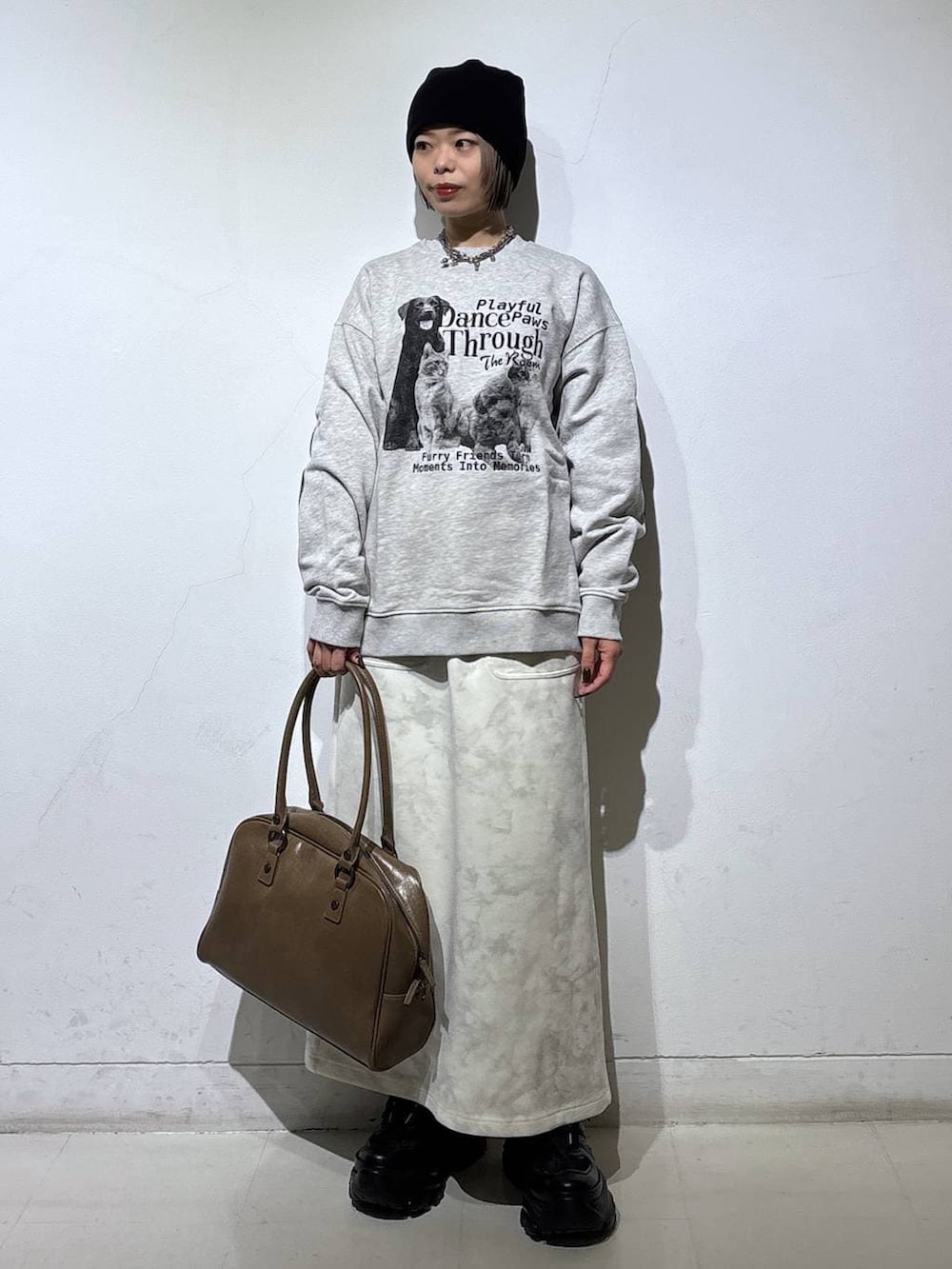 ブラック系のスニーカー、ベージュ系のボストンバッグ、ホワイト系のスカートを着用したレディースの冬コーディネートの4枚目の写真