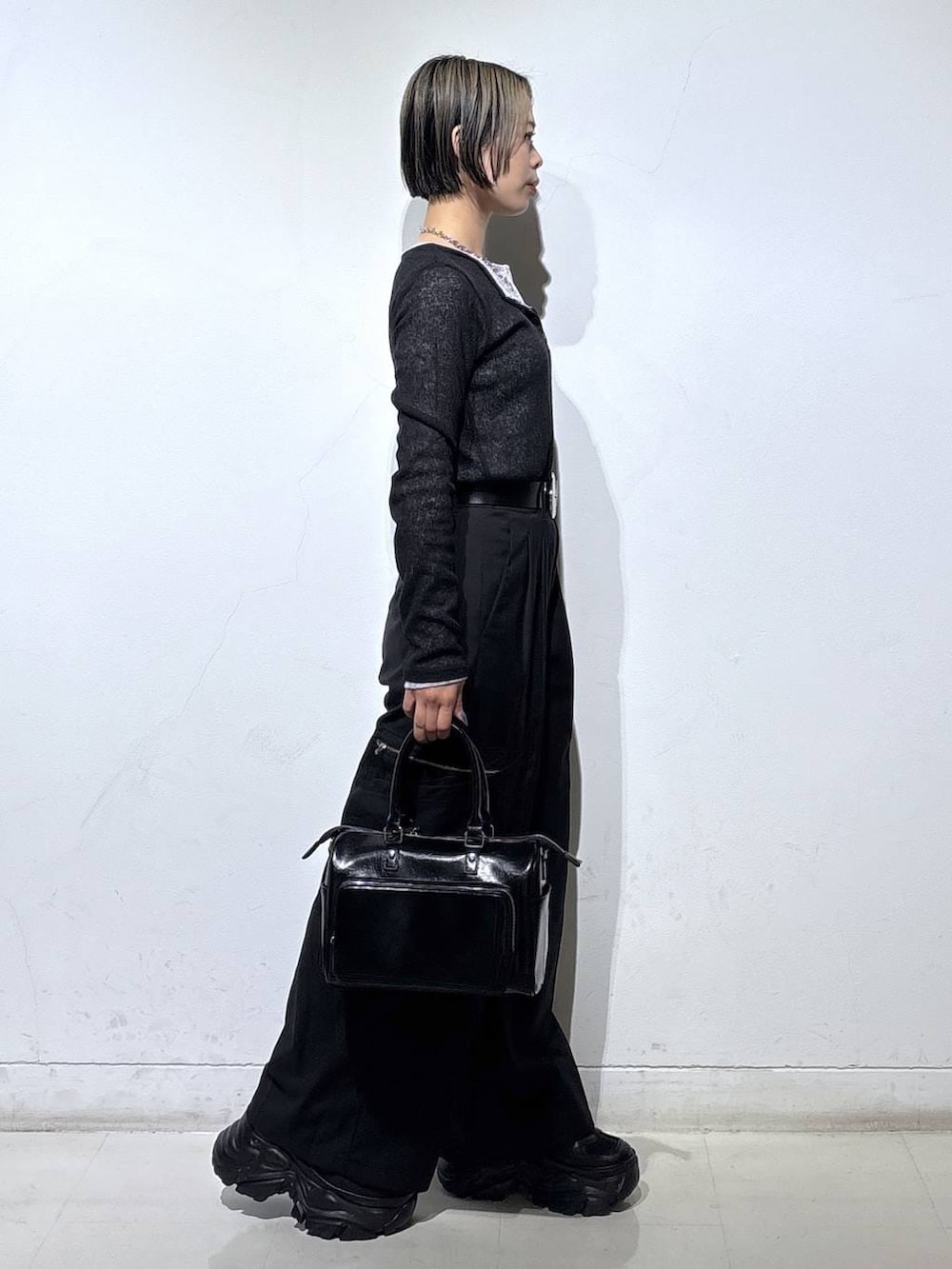 ブラック系のスニーカー、ブラック系のショルダーバッグ、ブラック系のスラックスを着用したレディースの冬コーディネートの4枚目の写真