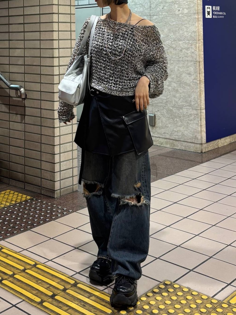 ブラック系のスニーカー、ブラック系のニット/セーター、シルバー系のハンドバッグを着用したレディースの春コーディネートの6枚目の写真