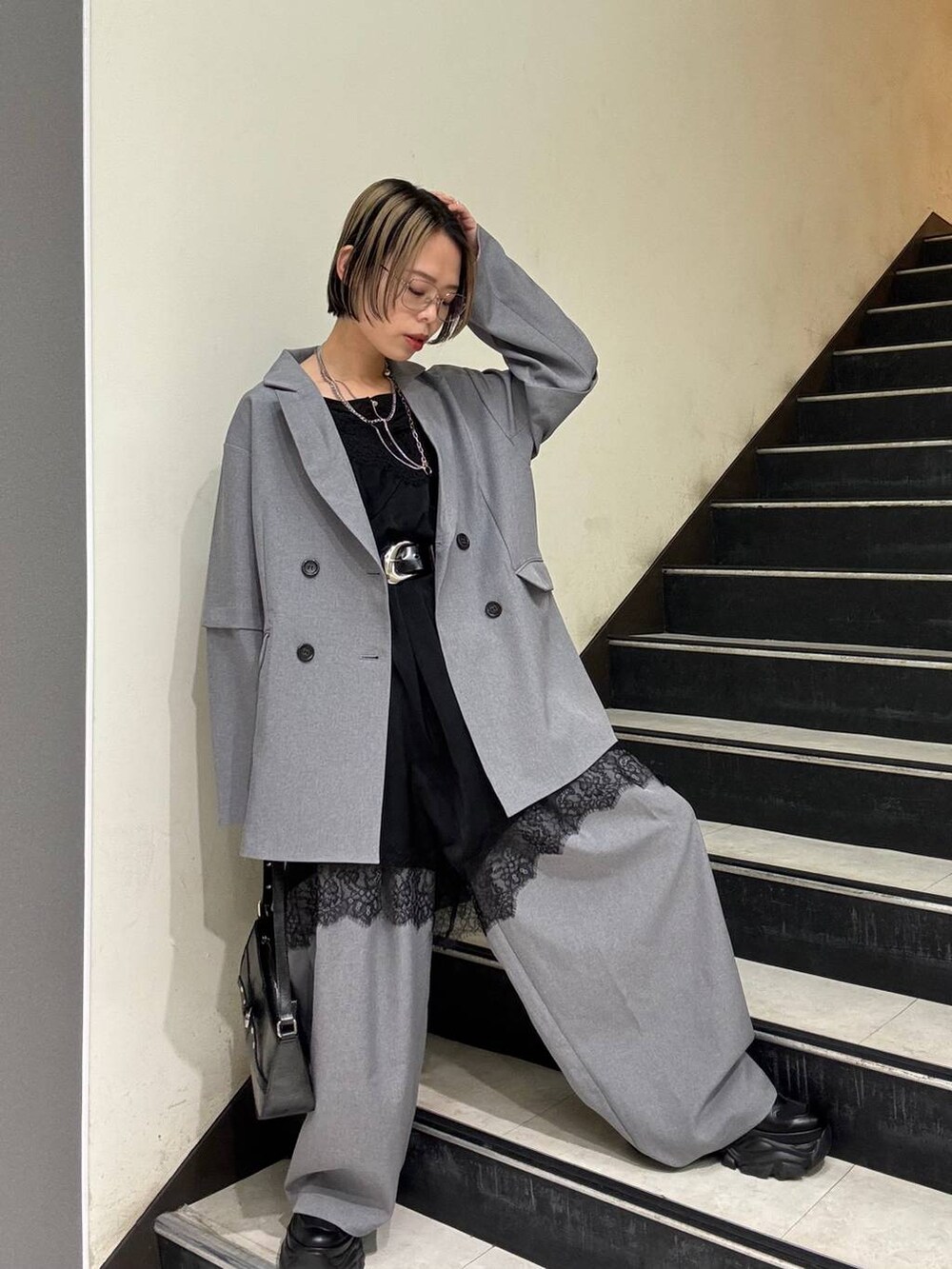 ブラック系のスニーカー、ブラック系のチュニック、ブラック系のハンドバッグを着用したレディースの春コーディネートの2枚目の写真