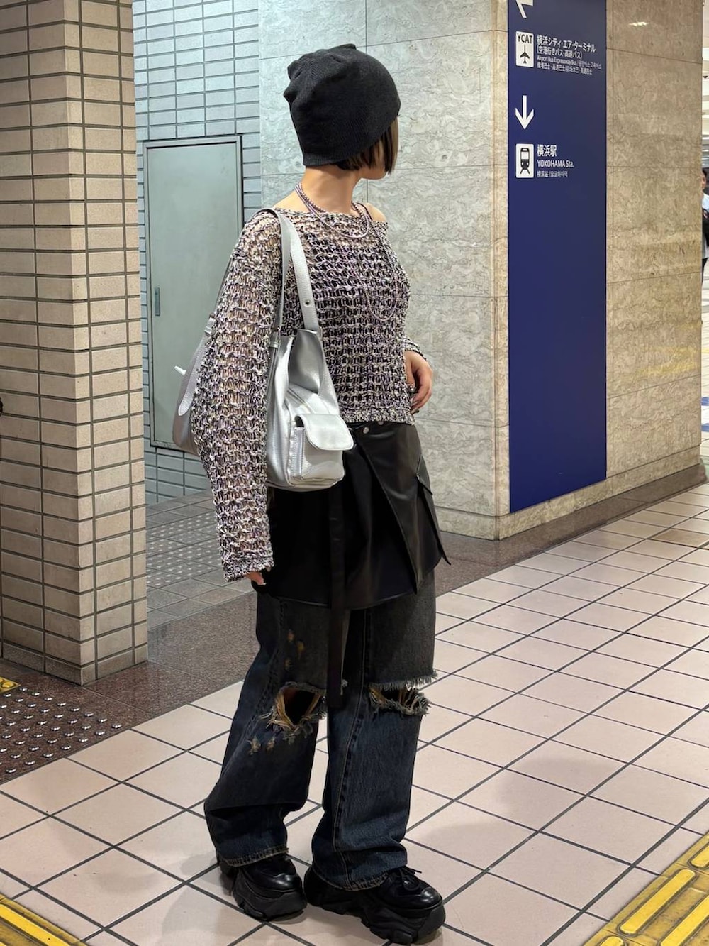 ブラック系のスニーカー、ブラック系のニット/セーター、シルバー系のハンドバッグを着用したレディースの春コーディネートの2枚目の写真