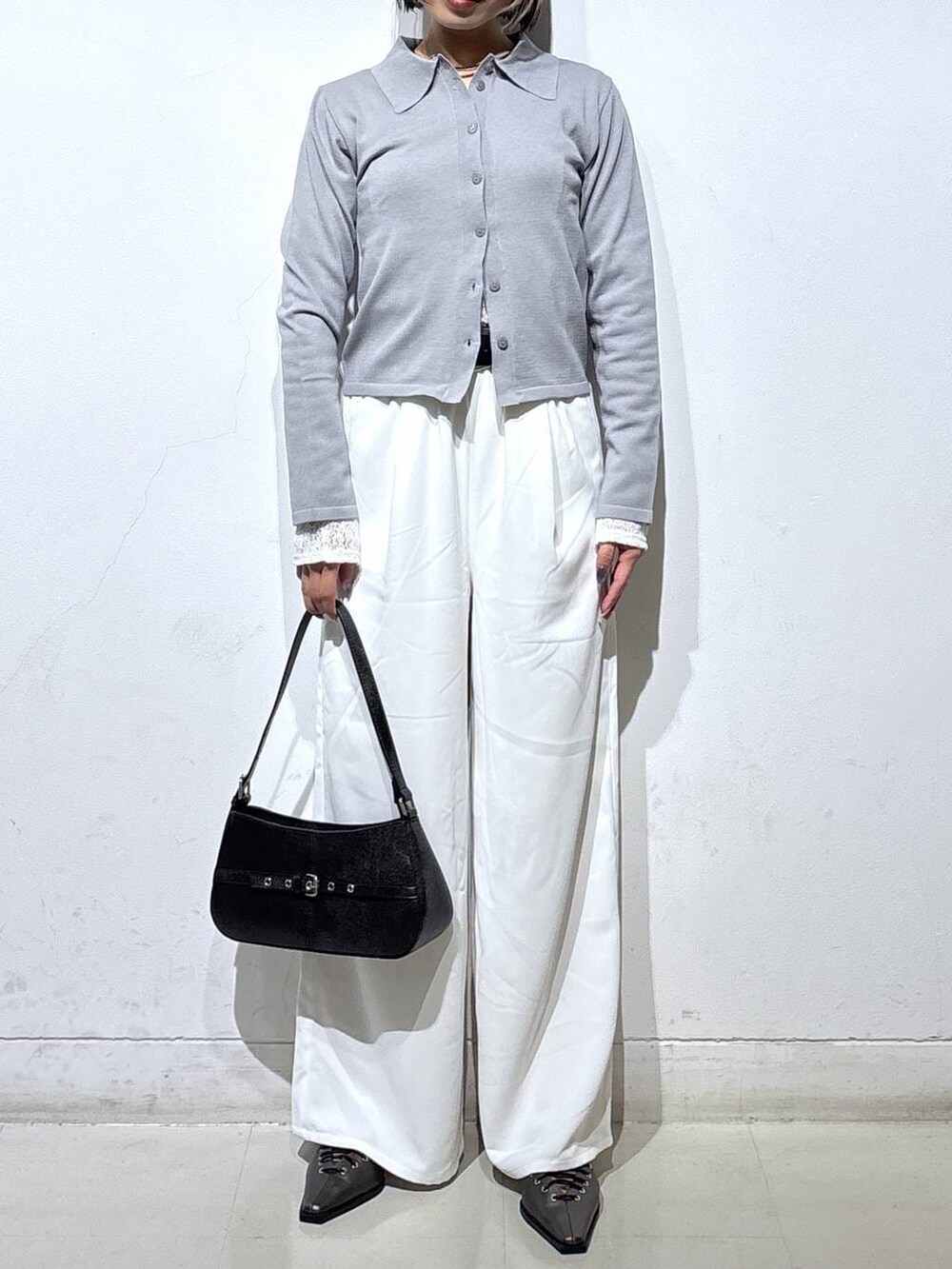 ブラック系のハンドバッグ、ブラウン系のサンダル、ホワイト系のスラックスを着用したレディースの春コーディネートの2枚目の写真