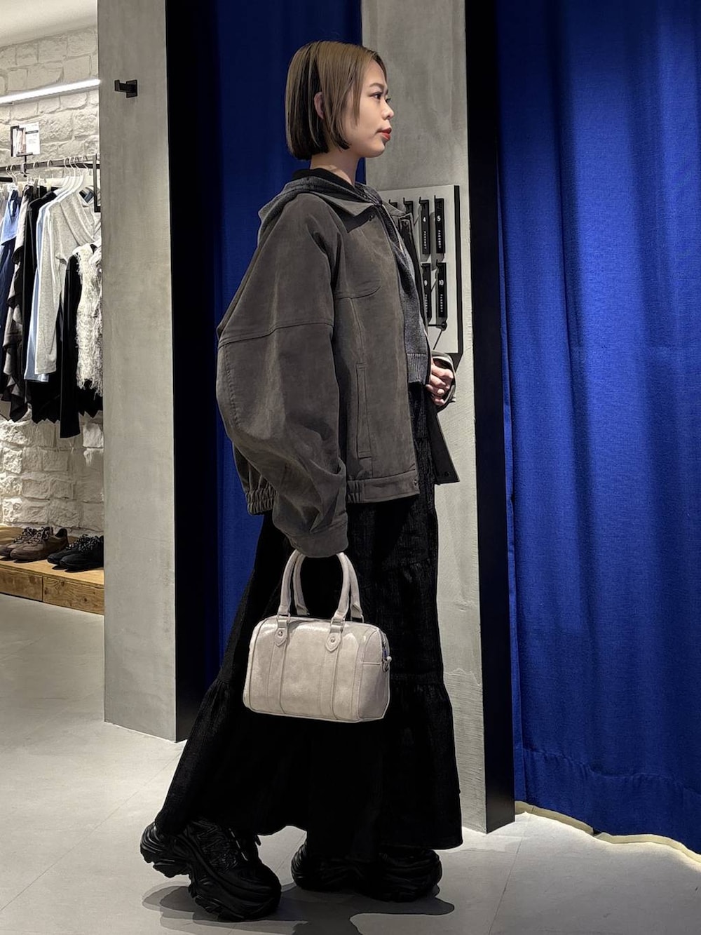 ブラック系のスニーカー、ホワイト系のボストンバッグ、グレー系のパーカーを着用したレディースの冬コーディネートの4枚目の写真