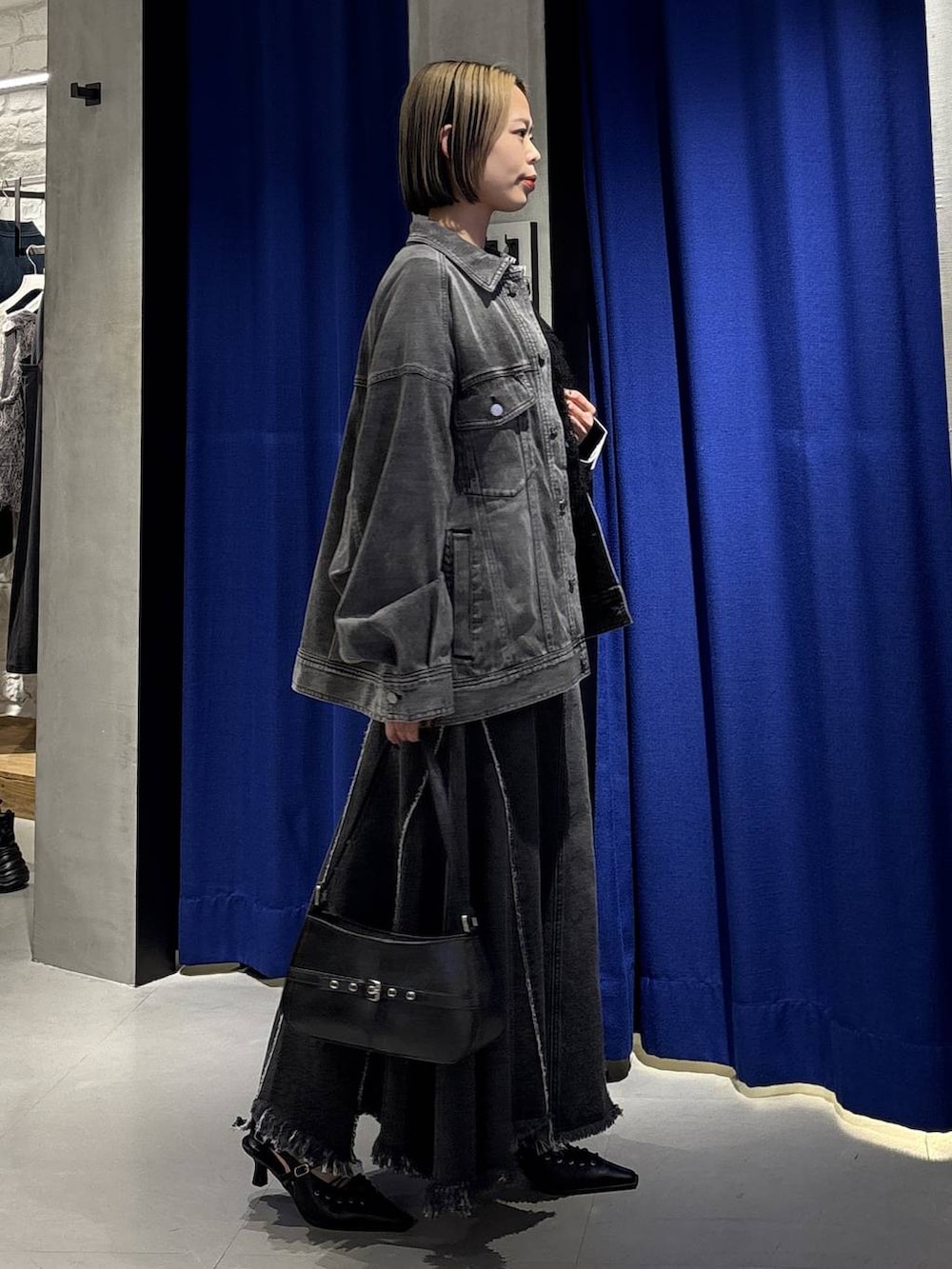 ブラック系のハンドバッグ、ブラック系のブルゾン、ブラック系のサンダルを着用したレディースの春コーディネートの3枚目の写真