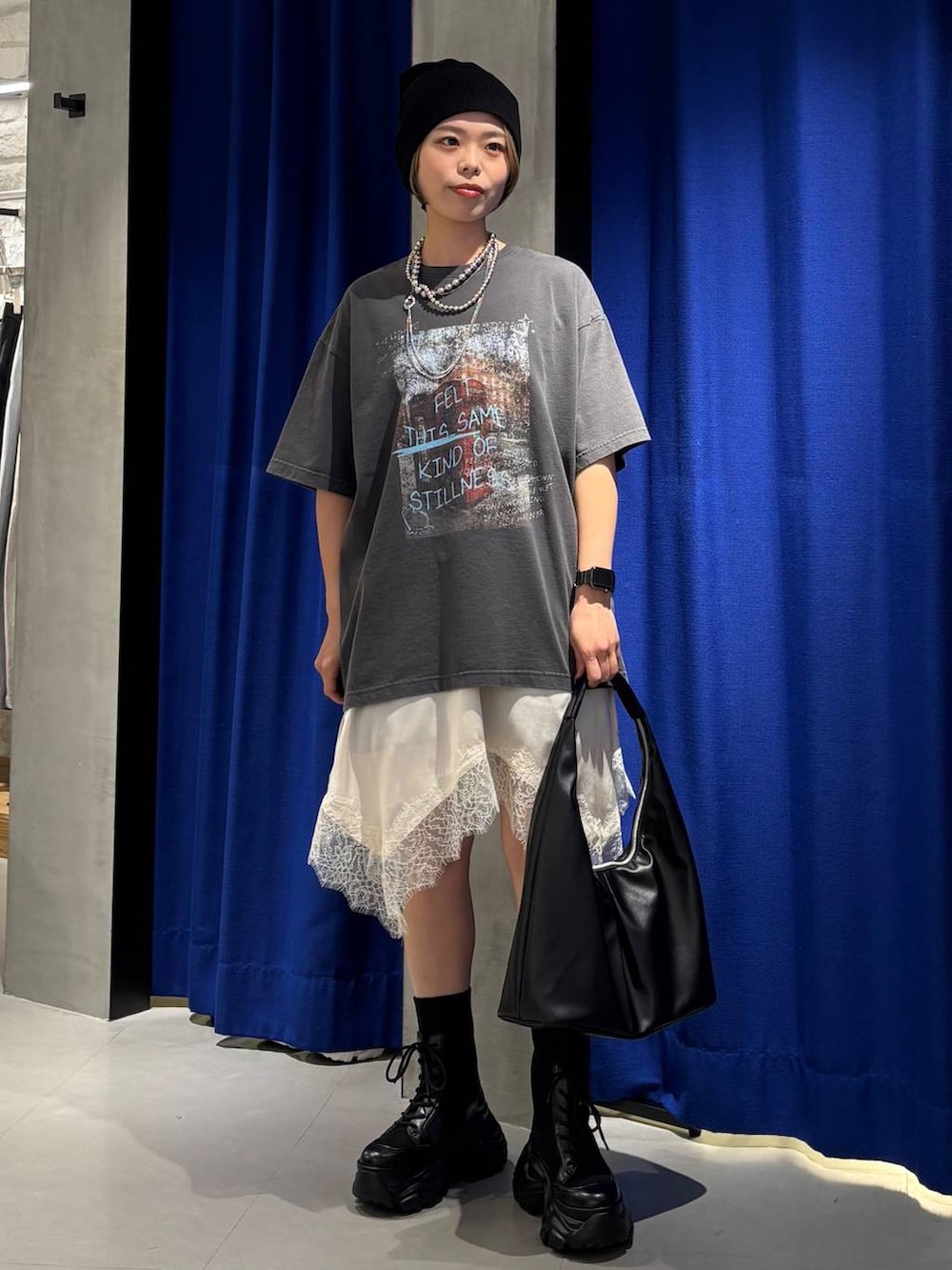 ブラック系のブーツ、ブラック系のトートバッグ、ホワイト系のチュニックを着用したレディースの春コーディネートの3枚目の写真