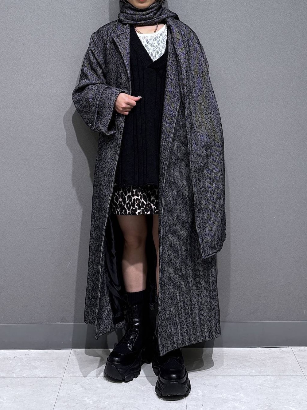 ブラック系のブーツ、ブラック系のチェスターコート、ホワイト系のTシャツ/カットソーを着用したレディースの冬コーディネートの2枚目の写真