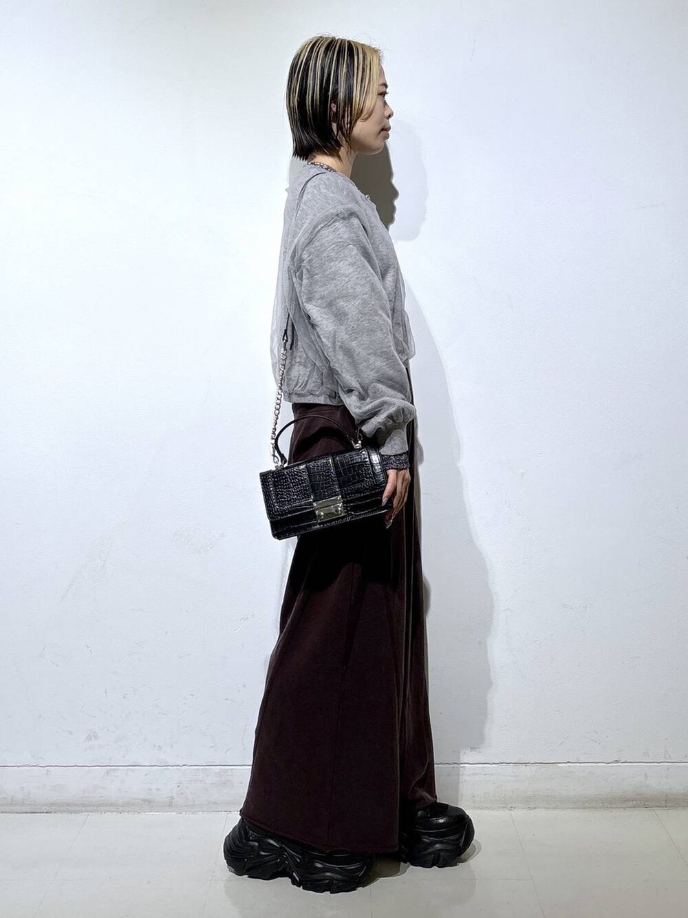 ブラック系のブーツ、シルバー系のTシャツ/カットソー、ブラウン系のスウェットパンツを着用したレディースの秋コーディネートの3枚目の写真